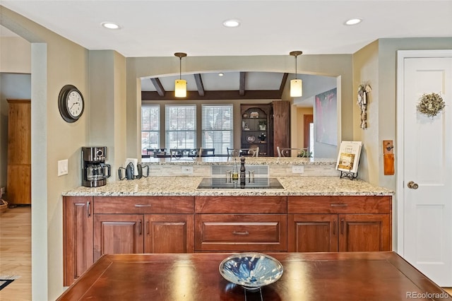 kitchen featuring light stone countertops, sink, beamed ceiling, pendant lighting, and wood-type flooring