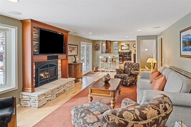 living room with light wood-type flooring and a stone fireplace