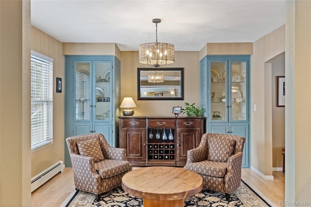 sitting room featuring an inviting chandelier, light wood-type flooring, and a baseboard heating unit