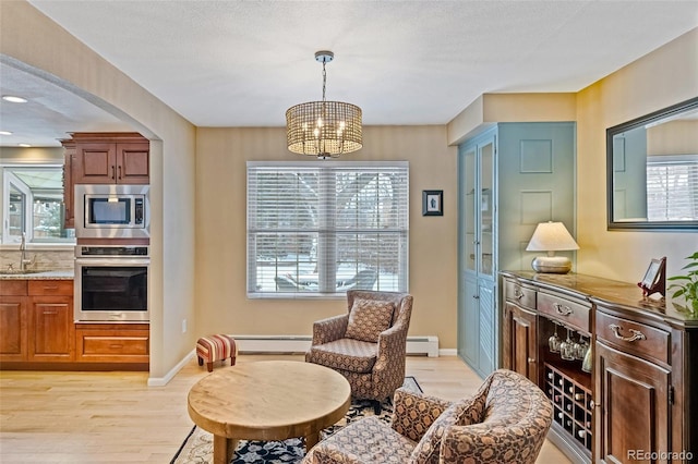 sitting room with light hardwood / wood-style flooring, plenty of natural light, a baseboard heating unit, and sink