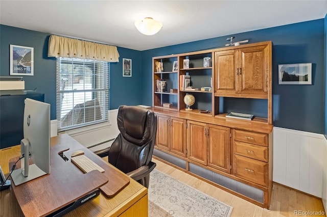 home office with light hardwood / wood-style floors and a baseboard heating unit