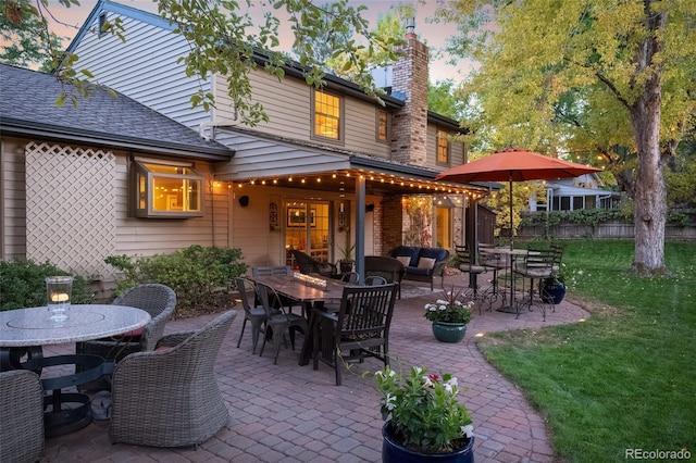 patio terrace at dusk featuring a lawn