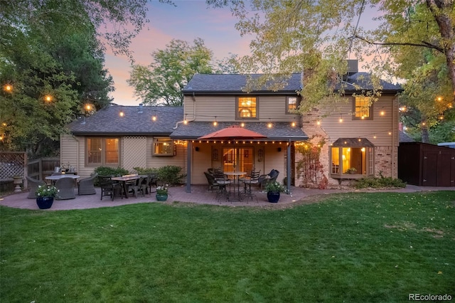 back house at dusk featuring a patio area, a yard, and a shed