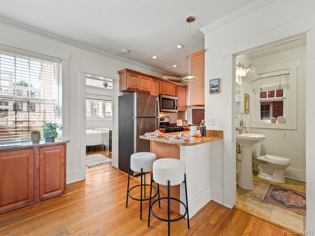945 N Washington St Unit 201, Denver, CO 80203 - kitchen featuring light wood-style flooring, light stone counters, a kitchen bar, a peninsula, and appliances with stainless steel finishes