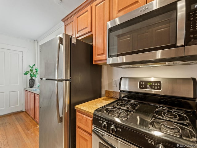 945 N Washington St Unit 201, Denver, CO 80203 - kitchen featuring appliances with stainless steel finishes, light countertops, light wood-style flooring, ornamental molding, and brown cabinets