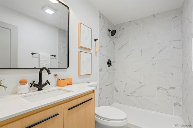 bathroom with a tile shower, vanity, and toilet