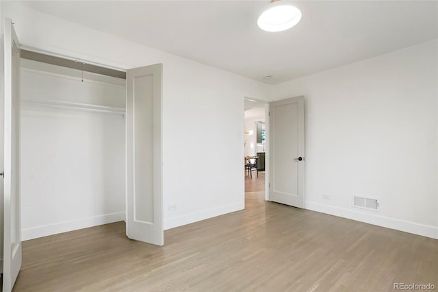 unfurnished bedroom with light wood-type flooring and a closet