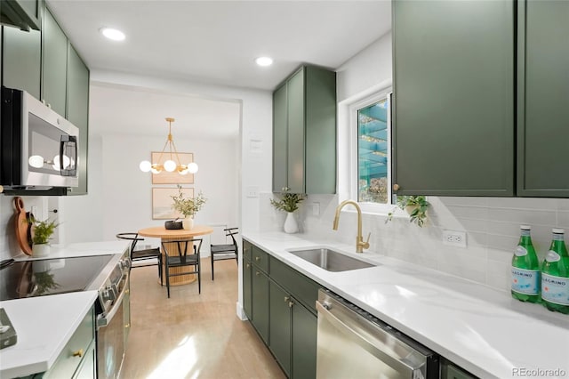 kitchen featuring sink, stainless steel appliances, light hardwood / wood-style floors, decorative backsplash, and green cabinetry