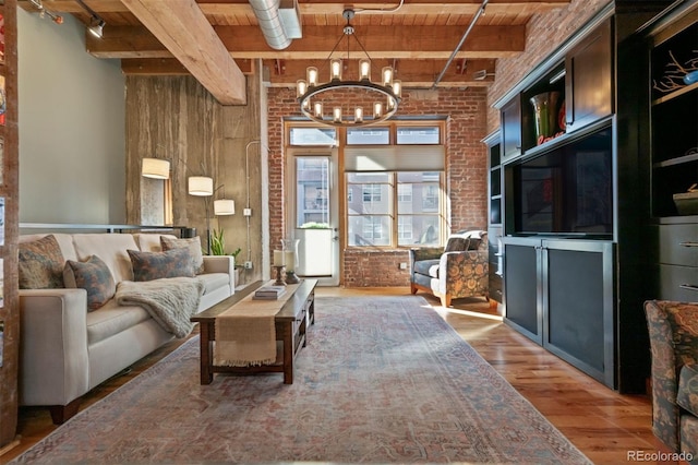 living area with a notable chandelier, brick wall, wood finished floors, wooden ceiling, and beamed ceiling