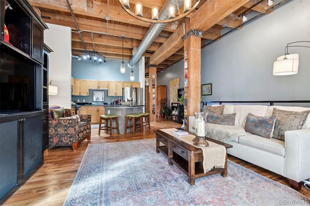 living room with a towering ceiling and light wood-type flooring