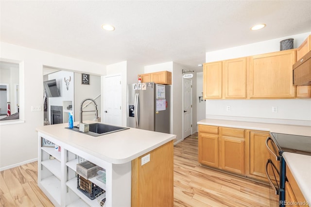 kitchen featuring sink, light hardwood / wood-style flooring, stainless steel appliances, and an island with sink