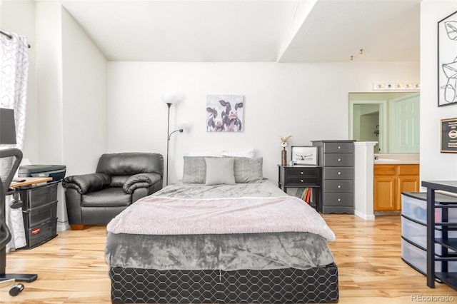 bedroom with connected bathroom and light hardwood / wood-style floors