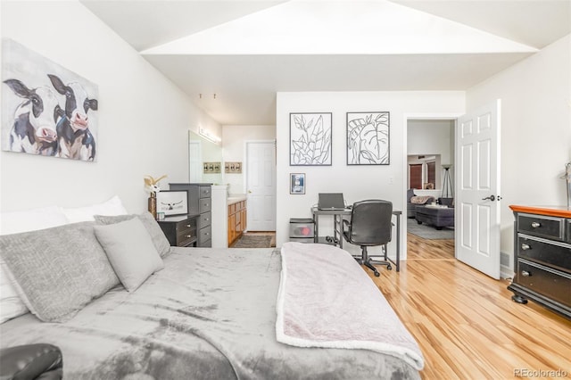 bedroom with lofted ceiling, connected bathroom, and hardwood / wood-style floors