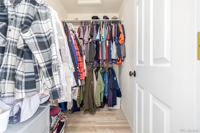 walk in closet with light hardwood / wood-style floors