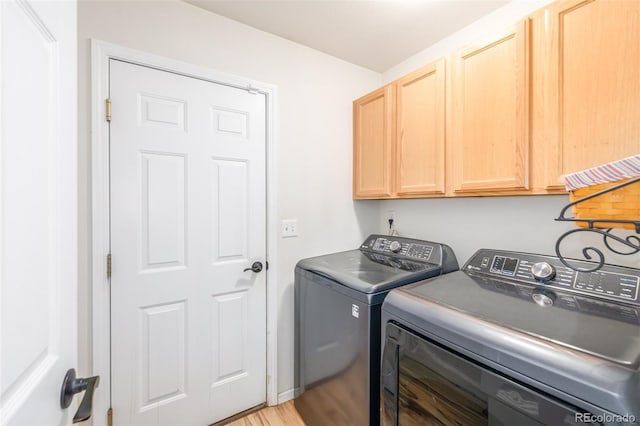 laundry room with separate washer and dryer, light hardwood / wood-style floors, and cabinets