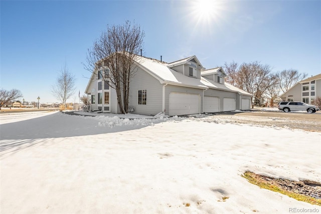 snow covered property with a garage