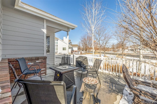 snow covered patio with an outdoor fire pit