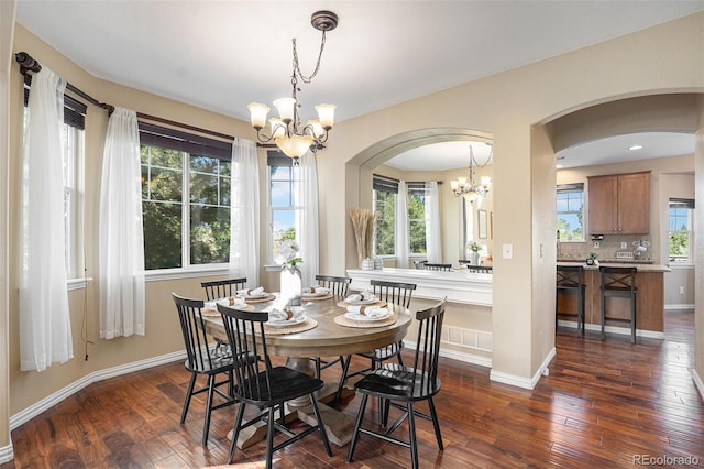 7624 Russell Ct, Arvada, CO 80007 - dining space featuring a chandelier, arched walkways, dark wood-style floors, and baseboards