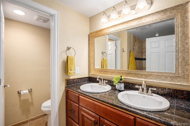 7624 Russell Ct, Arvada, CO 80007 - full bathroom featuring toilet, double vanity, and tasteful backsplash