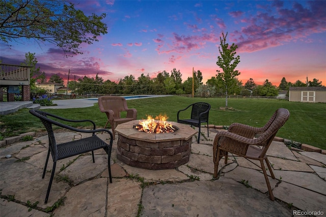 7624 Russell Ct, Arvada, CO 80007 - patio terrace at dusk featuring an outdoor fire pit, a patio area, a yard, and an outdoor structure
