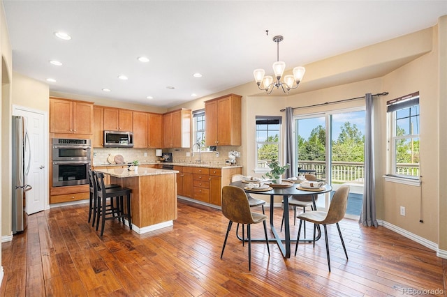 7624 Russell Ct, Arvada, CO 80007 - kitchen with appliances with stainless steel finishes, a sink, a chandelier, a kitchen island, and backsplash