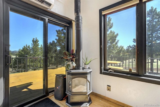 doorway to outside with wood finished floors, baseboards, and a wood stove
