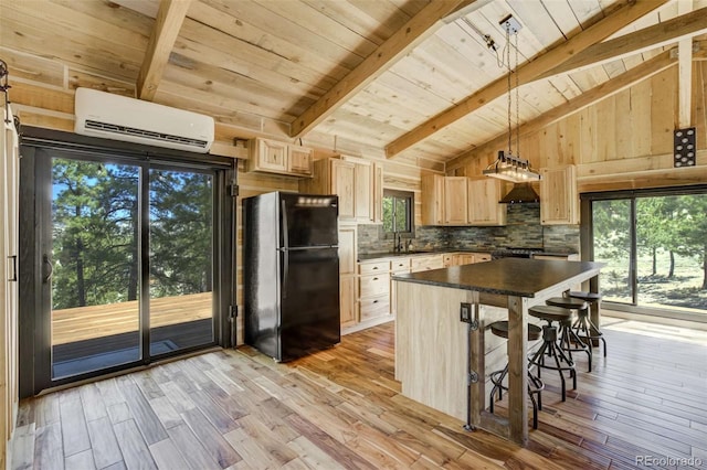 kitchen featuring freestanding refrigerator, an AC wall unit, light brown cabinetry, wooden ceiling, and dark countertops