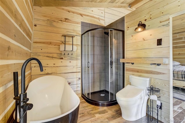 bathroom with wood walls, a sink, a shower stall, wood finished floors, and a freestanding tub