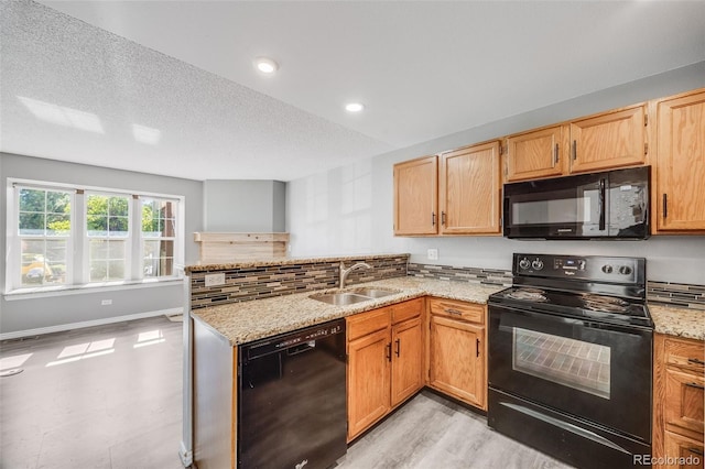 3090 W 107th Pl Unit F, Westminster, CO 80031 - kitchen with black appliances, a peninsula, light stone counters, recessed lighting, and light wood-type flooring