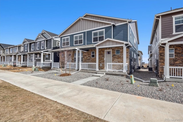 22384 E 6th Pl, Aurora, CO 80018 - view of front of property featuring board and batten siding, stone siding, covered porch, and central AC unit