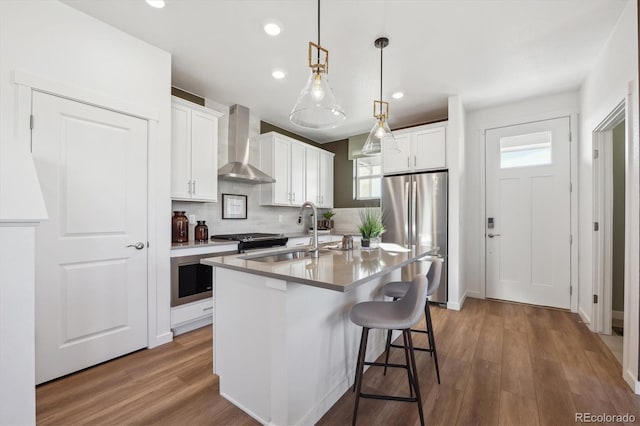 22384 E 6th Pl, Aurora, CO 80018 - kitchen with wall chimney range hood, freestanding refrigerator, a sink, tasteful backsplash, and a kitchen island with sink