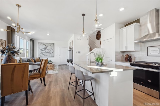 22384 E 6th Pl, Aurora, CO 80018 - kitchen with wall chimney range hood, stainless steel electric range, tasteful backsplash, white cabinets, and an island with sink