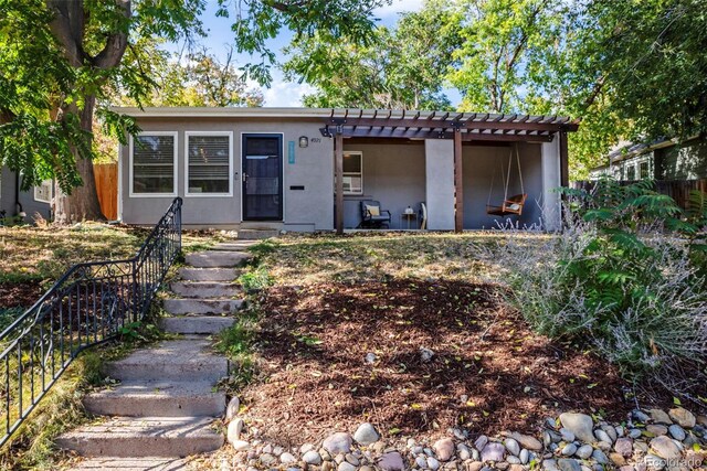 view of front facade with a pergola, fence, stairs, and stucco siding