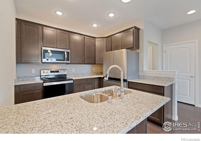 kitchen featuring dark brown cabinets, light stone counters, sink, and appliances with stainless steel finishes