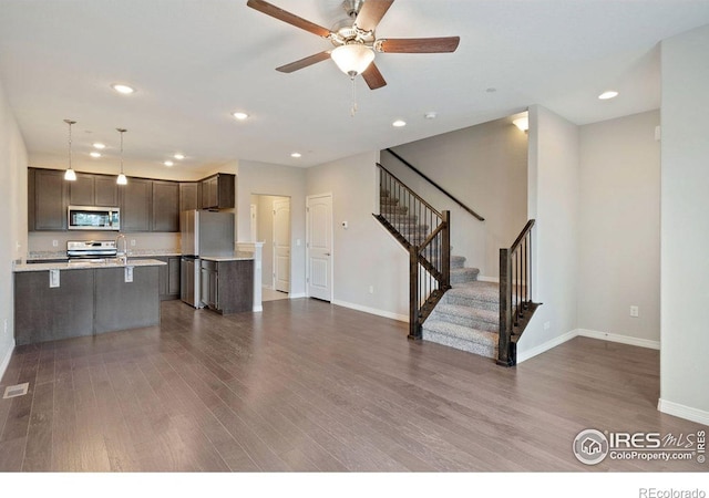 unfurnished living room featuring dark hardwood / wood-style flooring, ceiling fan, and sink