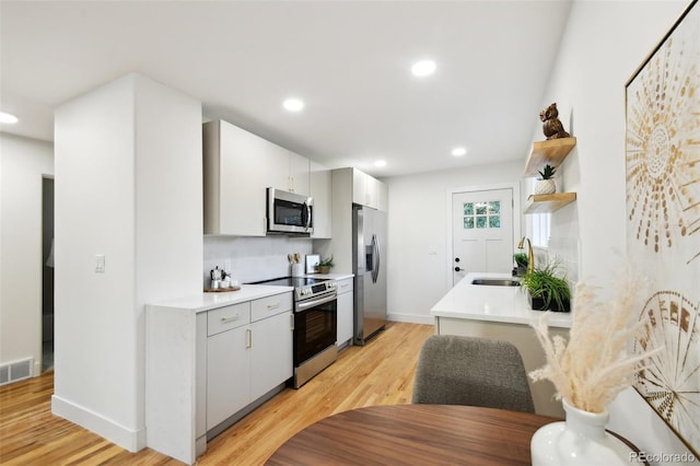 kitchen featuring white cabinetry, light wood-type flooring, sink, and appliances with stainless steel finishes