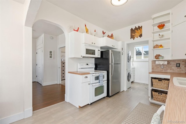 224 4th Ave, Severance, CO 80550 - kitchen with white appliances, stacked washer / dryer, arched walkways, open shelves, and light wood-style flooring