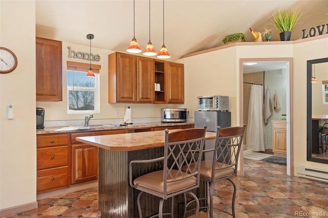 224 4th Ave, Severance, CO 80550 - kitchen featuring stainless steel microwave, brown cabinetry, light countertops, a kitchen island, and a kitchen bar