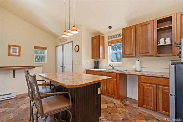224 4th Ave, Severance, CO 80550 - kitchen featuring freestanding refrigerator, a kitchen bar, light countertops, a center island, and brown cabinets