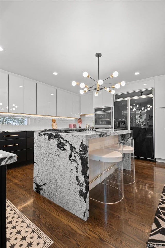 2062 Hyacinth Rd, Highlands Ranch, CO 80129 - kitchen with black fridge, modern cabinets, a chandelier, white cabinetry, and recessed lighting