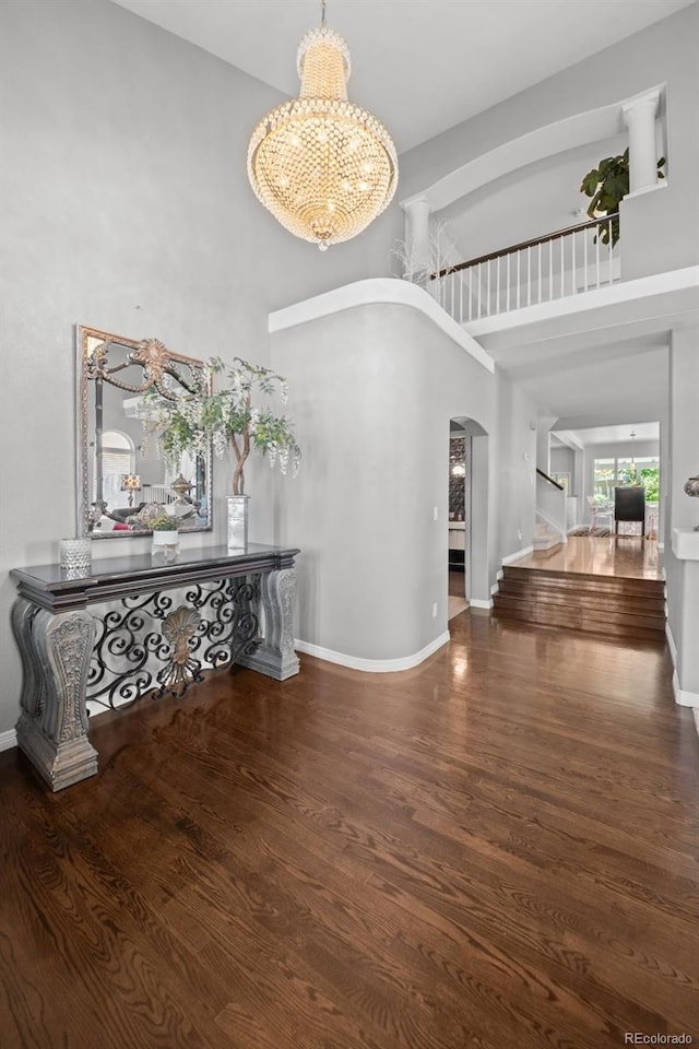 2062 Hyacinth Rd, Highlands Ranch, CO 80129 - corridor featuring a high ceiling, arched walkways, a chandelier, wood finished floors, and stairway