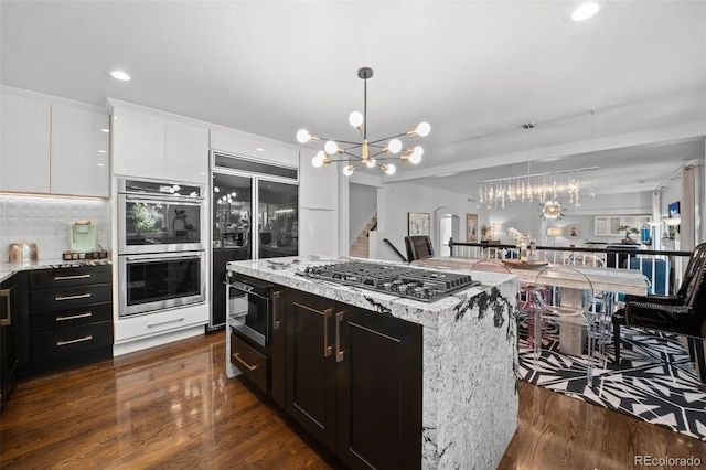 2062 Hyacinth Rd, Highlands Ranch, CO 80129 - kitchen with a chandelier, built in appliances, dark wood-type flooring, hanging light fixtures, and white cabinets