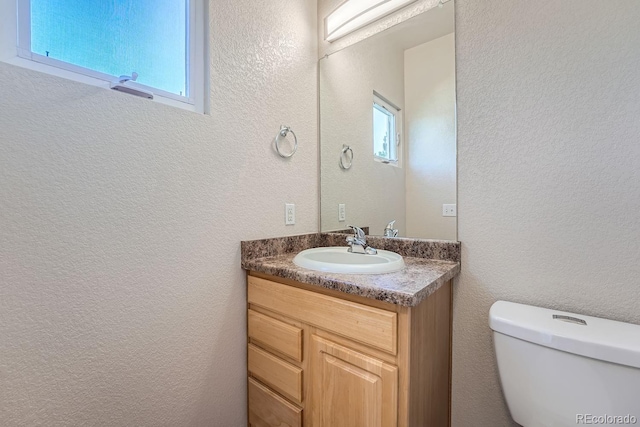 bathroom with toilet, plenty of natural light, and vanity