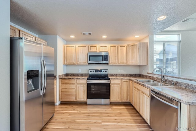 kitchen with sink, stainless steel appliances, light hardwood / wood-style flooring, and light brown cabinetry