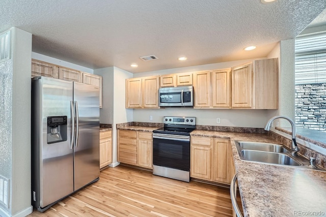 kitchen featuring appliances with stainless steel finishes, sink, light hardwood / wood-style flooring, and light brown cabinets