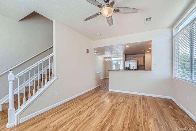 unfurnished living room featuring ceiling fan, a textured ceiling, light hardwood / wood-style flooring, and a wealth of natural light