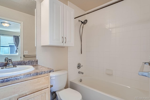 full bathroom with a textured ceiling, toilet, tiled shower / bath, and vanity