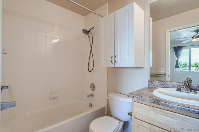 full bathroom with tiled shower / bath, a textured ceiling, vanity, ceiling fan, and toilet