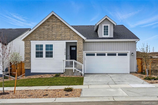 view of front facade with board and batten siding, a garage, stone siding, fence, and concrete driveway
