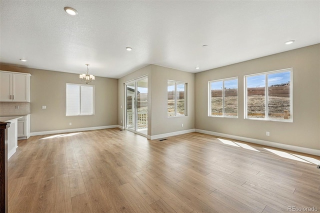 unfurnished living room with baseboards, recessed lighting, and an inviting chandelier